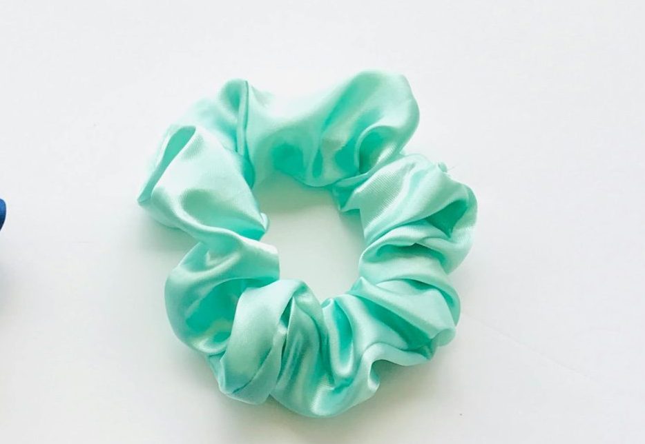 Luxurious satin hair accessories including scrunchies and a bonnet in vibrant blue and mint green.